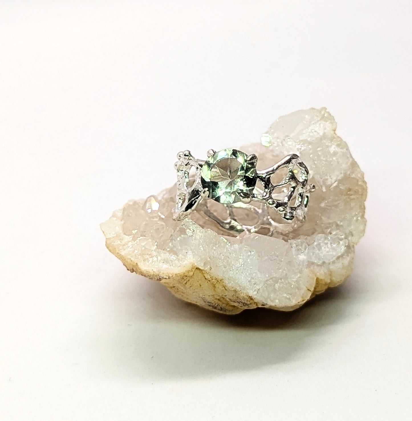 Silver ring with a green gemstone on a white background